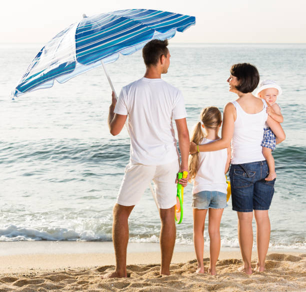 istock back view on family of four standing on beach 1166156436