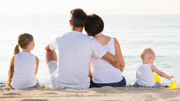 istock back view on family of four sitting on beach 1166156465