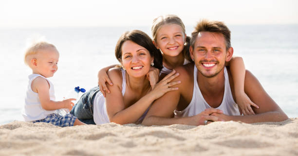 istock parents with two kids lying on the beach 1166156493
