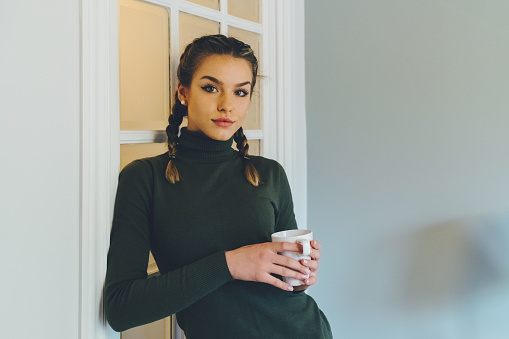 Young woman holding a cup of tea and looking at camera