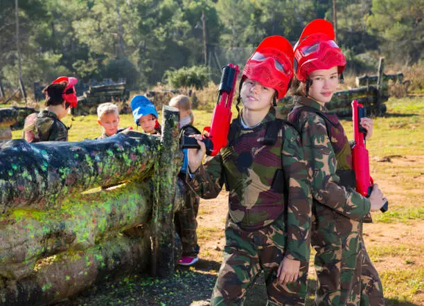 Photo of two girls paintball players with marker guns ready for game
