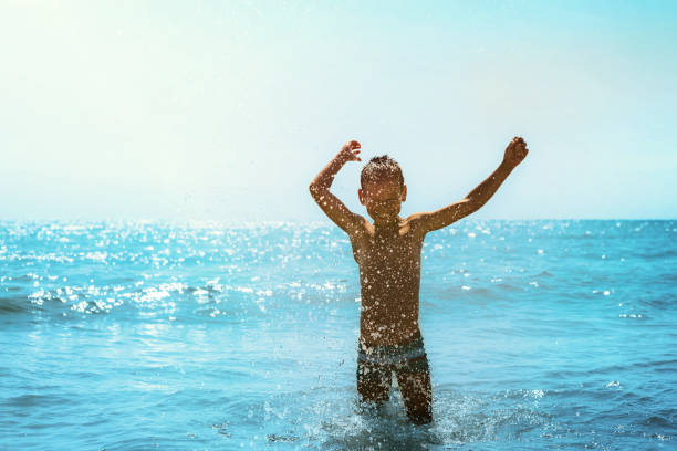 istock a kid running on the seashore with waves 1166159954