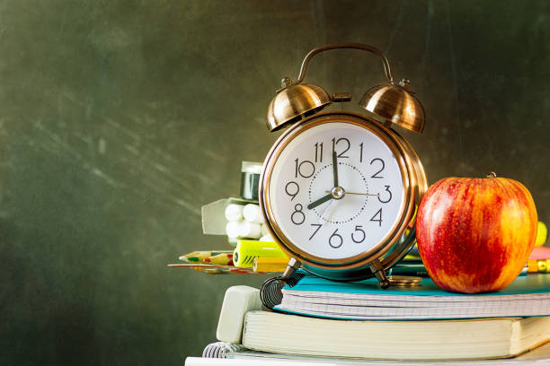 istock Stack of workbooks pens pencils alarm clock red apple on vintage scratched chalkboard background. Back to school education learning studying concept. Poster banner with copy space 1166161066