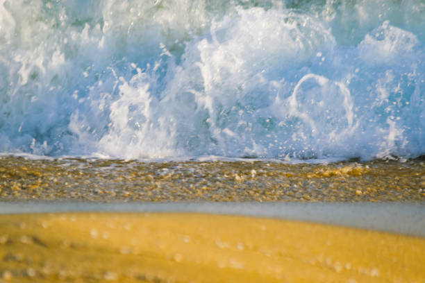 Close up sea waves splash on sandy beach.