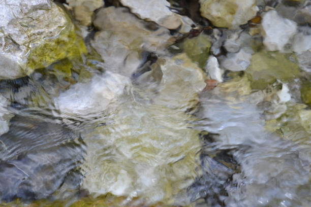 Transparent close-up view to stones on bottom of a mountain stream of pure flowing water.