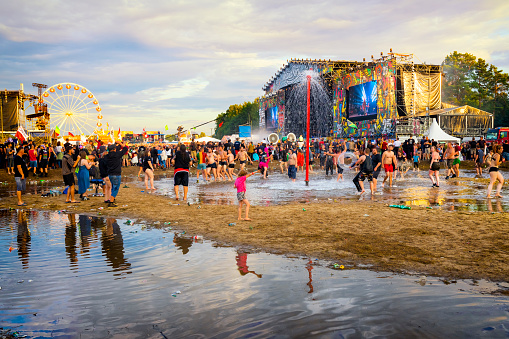 Kostrzyn Nad Odra, Poland - August 03, 2019: Crowd of young people cheerfully spends time bathing in the mud, sitting and standing in front of main stage at 25th Pol'and'rock Festival - the biggest open air ticket free rock music festival in Europe