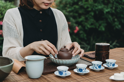Young adult chinese woman doing tea ceremony outdoor