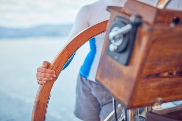 istock Sailor using wheel to steer rudder on a sailing boat. 1166166575