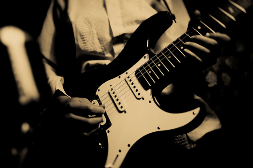 Close-up of an electric guitar on a black background. Monochrome photography. Selective narrow focus on pickup, free space for text