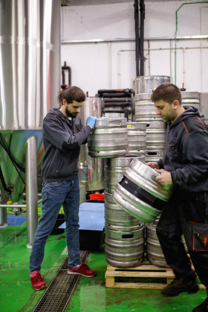 istock Brewers in storage room taking kegs 1166168643