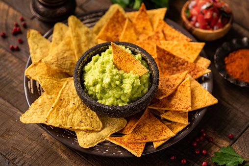 Guacamole avocado sauce, traditional mexican nachos and tortilla chips with paprika