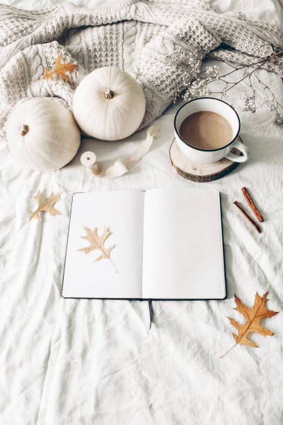 istock Autumn breakfast in bed composition. Blank open notebook mockup. Cup of coffee, white pumpkins, sweater, oak leaves and cinnamon on linen background. Thanksgiving, Halloween. Flat lay. Top view 1166170230