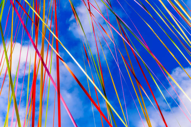Multicoloured ribbons stream between buildings against a blue sky.