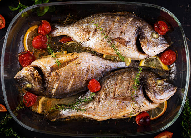 istock Baked fish dorado with lemon and herbs in baking pan on dark rustic background. Top view. Healthy dinner with fish concept. Dieting and clean eating 1166174192