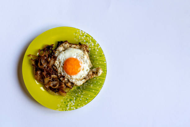 Green plate with fried egg and onion on a light background.