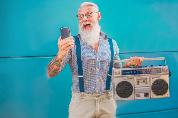 istock Senior hipster man using smartphone app for creating playlist music - Trendy tattoo guy having fun with mobile phone technology - Tech and joyful elderly lifestyle concept - Focus on his face 1166177371
