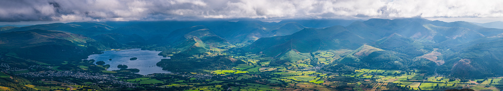 Aerial panoramic vista across the picturesque landscape of the Lake District National Park, Cumbria, UK, from the tranquil shores of Derwent Water, across the green pastures of Braithwaite to the dramatic ridges and peaks of the Western Fells.