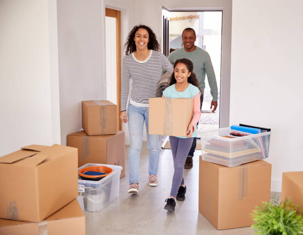 istock Smiling Family Carrying Boxes Into New Home On Moving Day 1166182990