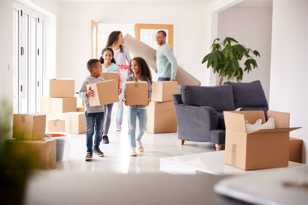istock Smiling Family Carrying Boxes Into New Home On Moving Day 1166183157