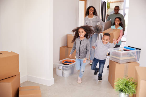 istock Smiling Family Carrying Boxes Into New Home On Moving Day 1166183352