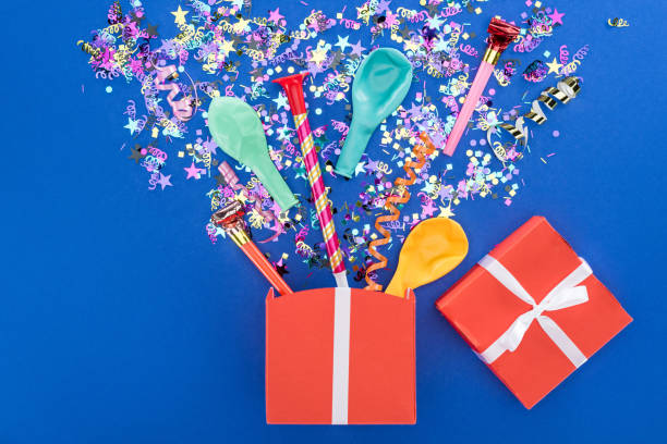 istock Red gift box and various party decor on blue background 1166184386
