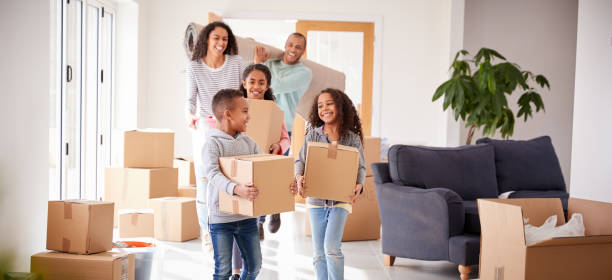 istock Smiling Family Carrying Boxes Into New Home On Moving Day 1166185364