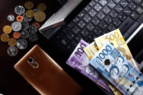 Laptop computer, coins, money and a smartphone Overhead photo of laptop computer, coins, money and a smartphone philippines currency stock pictures, royalty-free photos & images