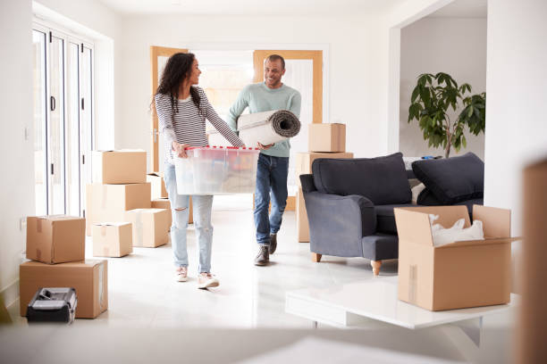 istock Smiling Couple Carrying Boxes Into New Home On Moving Day 1166187362