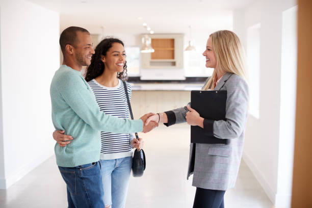 Female Real Estate Agent Shaking Hands With Couple Interested In Buying House Female Real Estate Agent Shaking Hands With Couple Interested In Buying House looking around stock pictures, royalty-free photos & images