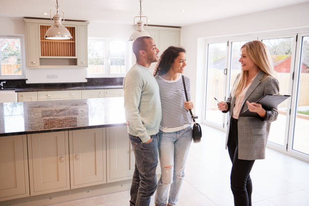 Female Real Estate Agent Showing Couple Interested In Buying Around House Female Real Estate Agent Showing Couple Interested In Buying Around House real estate agent photos stock pictures, royalty-free photos & images