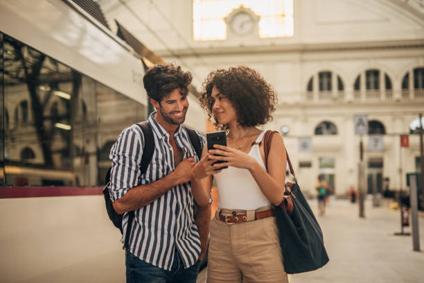 couple using phone on train station - tourists couple barcelona imagens e fotografias de stock