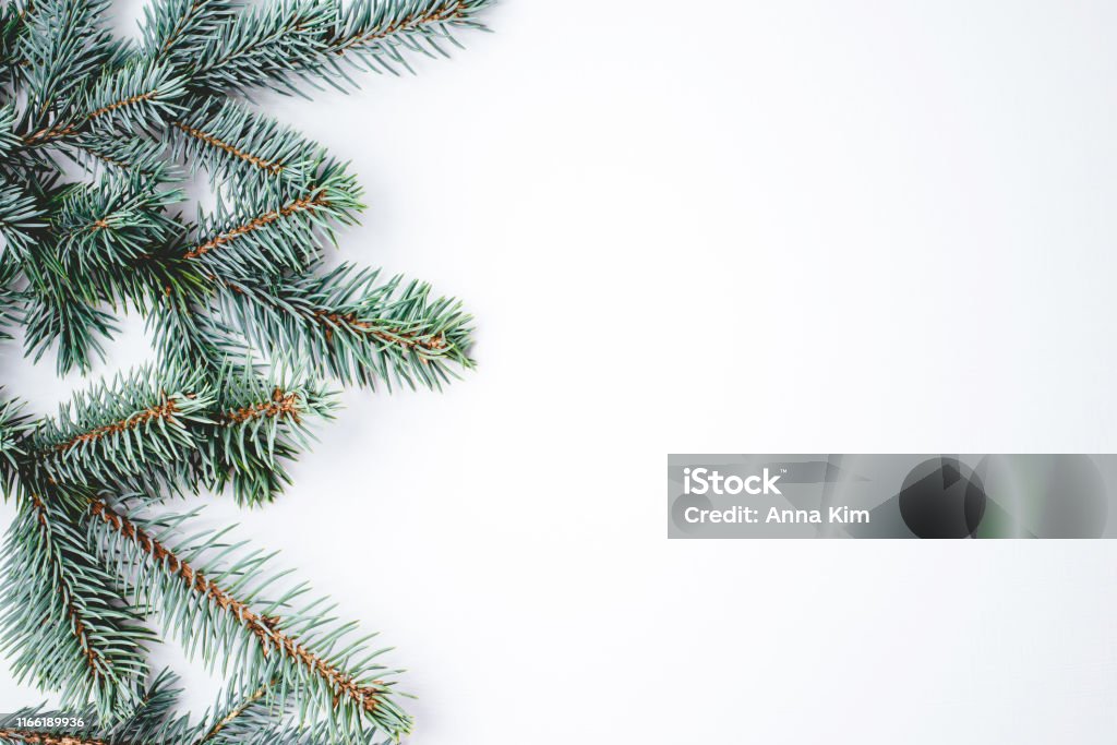 Fir branches on white background. Christmas wallpaper. Fir branches on white wooden background. Christmas wallpaper. Flat lay, copy space. 2020 Stock Photo