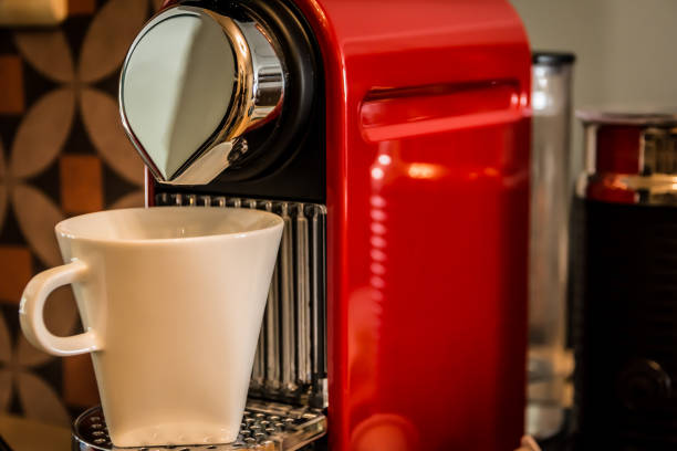 Close-up of a red cup-based coffee machine, pouring coffee in a white mug