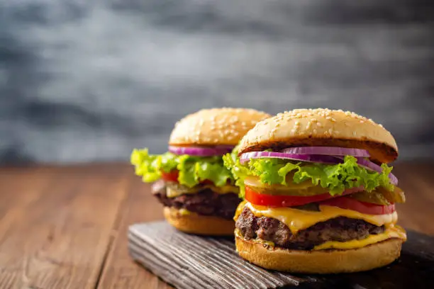 Photo of Two homemade tasty burgers on wood table