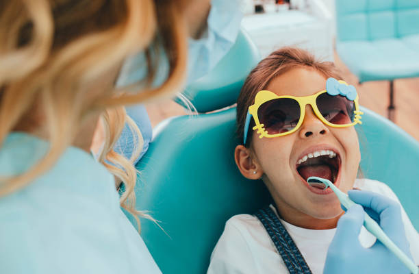 Cute little girl getting teeth exam at dental clinic stock photo