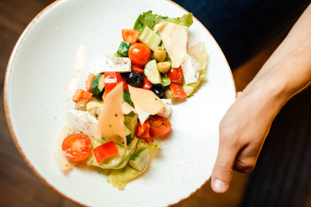 istock Greek salad in an original serving on a dish. Tomatoes, cheese, vegetables. 1166192171