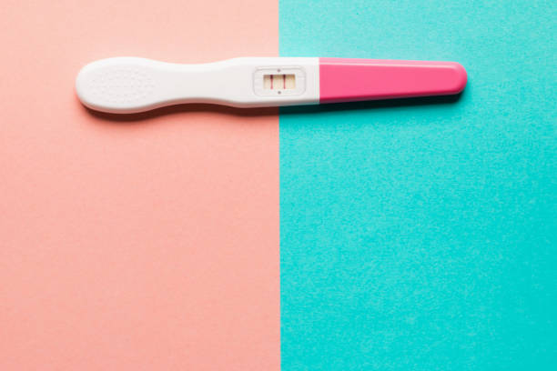 istock Positive pink plastic pregnancy test on pink and blue background 1166198747