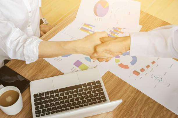 istock Businessmen holding hands team work analyzing charts agreeing to do business together 1166209179