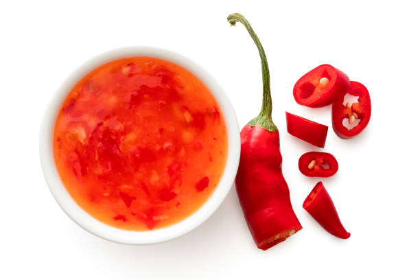 istock Sweet chilli sauce in a white ceramic bowl next to a cut up chilli pepper isolated on white from above. 1166209201