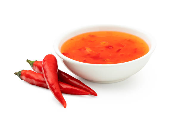 istock Sweet chilli sauce in a white ceramic bowl next to three red chillies isolated on white. 1166209238