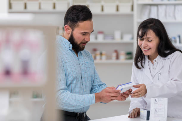 istock Pharmacist smiles as she and customer look at medicine box 1166209281