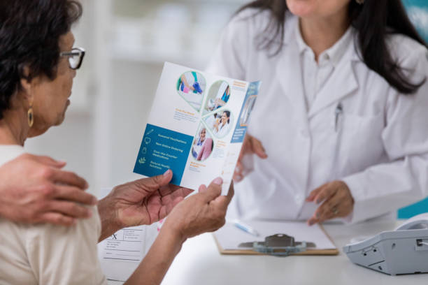 Senior woman examines pharmacy brochure Senior woman reads a pharmacy brochure while picking up a prescription. She is reading about the pharmacy's services. pamphlet stock pictures, royalty-free photos & images