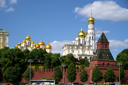 The wall and tower of Moscow Kremlin, Annunciation Cathedral, Assumption Cathedral, Bell tower of Ivan the great, Church of Archangel Michael. Moscow river embankment, blue sky. No recognizable people
