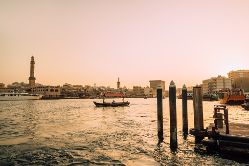 Skyline view of Dubai Creek with traditional boats and piers.