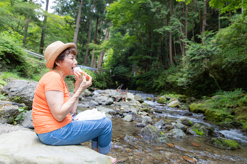 Senior woman eating lunch at riverbank