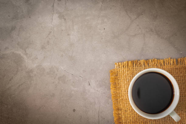 istock Cup of a black coffee and beans on sack with old cement floor. Top view, copy space 1166219263