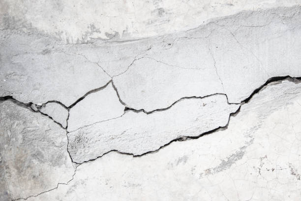 Grunge concrete wall at covered with gray cement old surface with crack in industrial building, great for your design and texture background. Black and white cracked floor texture vintage.