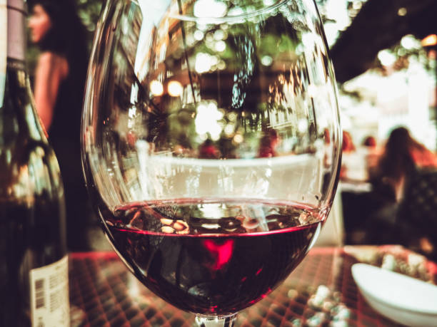 matte red wine glass and bottle at outdoors cafe restaurant bokeh
