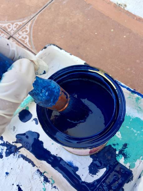 Hand holding paintbrush dipped in blue paint stock photo