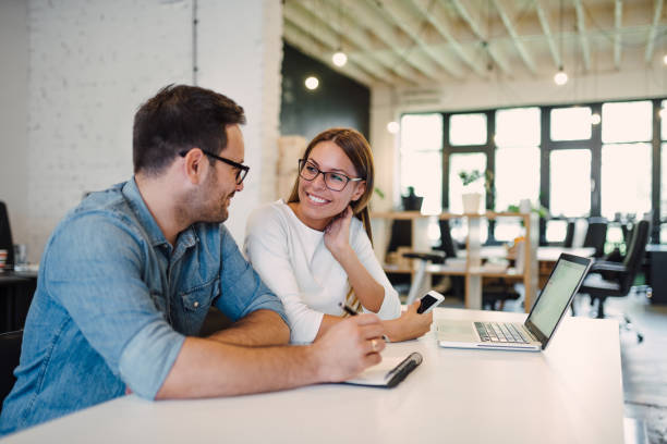istock Two beautiful young coworkers talking in modern office. 1166228189